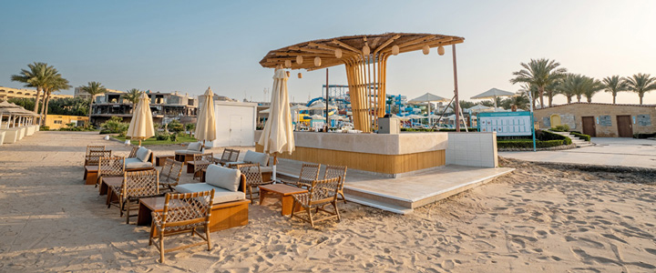 Die Strandbar des SUNRISE Azalea Aqua Park Resort lädt mit einer Lounge aus hellen Holzmöbeln zum entspannten Verweilen am Meer ein.