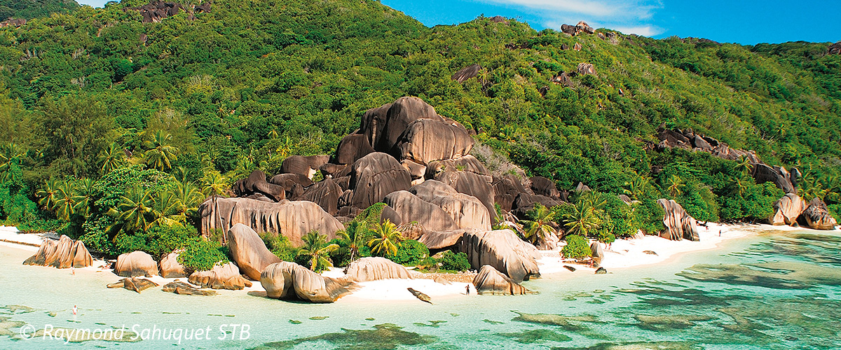 Die Anse Source d’Argent auf La Digue zeigt ihre charakteristischen Granitfelsen am türkisblauen Meer. Weißer Sand und tropisches Grün säumen die Küste.