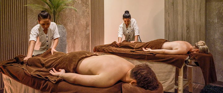 Zwei Personen genießen gleichzeitig eine entspannende Paarmassage auf bequemen Behandlungsliegen. Der moderne Spa-Bereich schafft eine ruhige Atmosphäre für erholsame Momente.